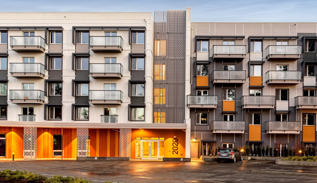 A real five-storey rental apartment facade with balconies and the address 2020 visible; associated source identifies Residences at Brechin Hill, 2020 Estevan Road, Nanaimo.