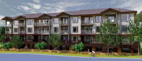 New three-storey wood-frame rental apartment surrounded by green gardens under blue skies.