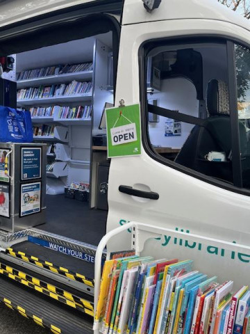 An open door into a van with shelves of books lining the walls.