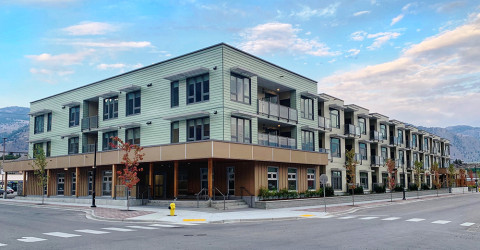 A modern three-storey apartment building situated on a street corner.