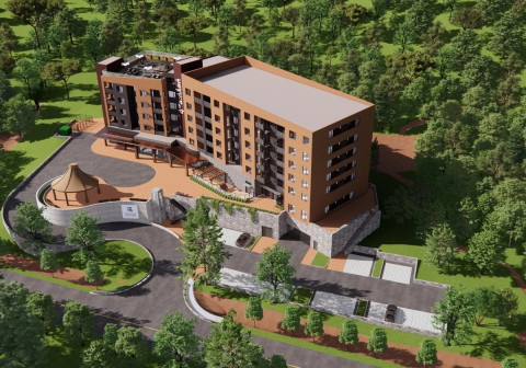 Aerial view of a modern, multi-story brick building nestled in a dense green forest, featuring large windows, balconies, a rooftop seating area, and a curved driveway leading to a canopied entrance with an adjacent circular structure topped by a conical roof.