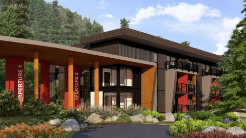 A modern building with a sleek design featuring large glass windows, wooden accents, and balconies. The building has two sections labelled 'Aperture 1' and 'Aperture 2' with red columns.