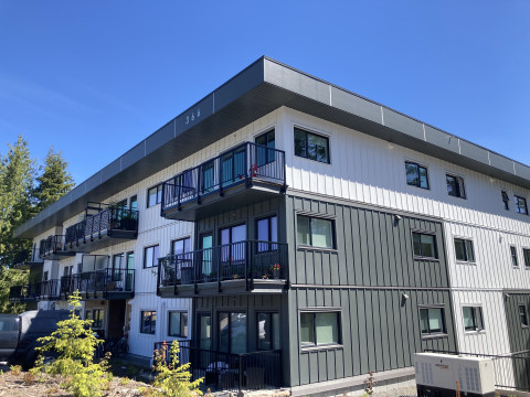 Angled view of a three-storey building with deep grey and white exterior walls.