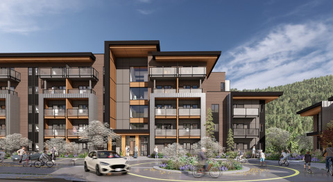 A modern multi-story residential building with large windows and balconies, set against a green hillside; people walk and cycle near a circular driveway as a white car passes under a partly cloudy sky.