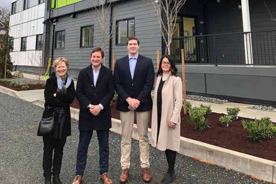 A group of four people posing in front of an apartment building.