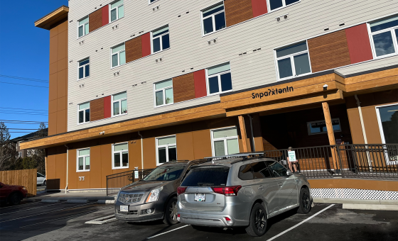 Four-storey building with light brown and beige walls, featuring a wooden canopy over the front door.