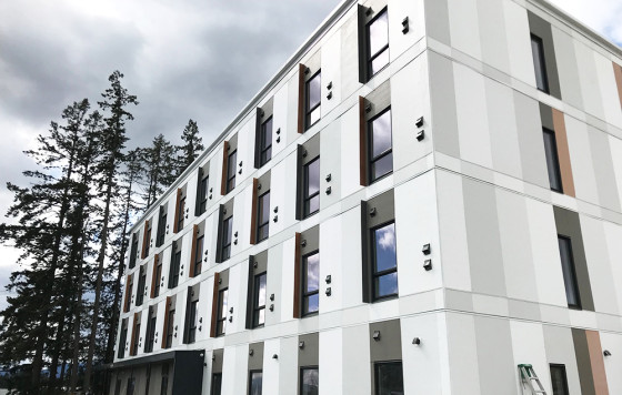 Exterior of Sq'umul' Shelh Lelum', a modern four-storey building with white and grey panels located at 6428 Paddle Road.