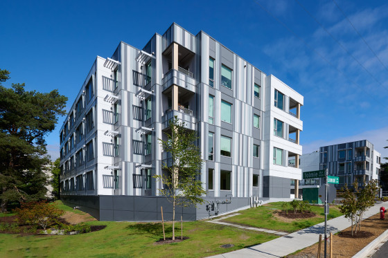 A modern multi-story building with a geometric facade featuring a combination of white panels and large glass windows.