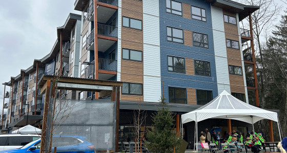 Exterior view of a new multi-unit rental building with an event tent set up nearby