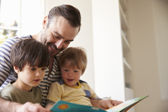 two young children sitting being read to by an adult