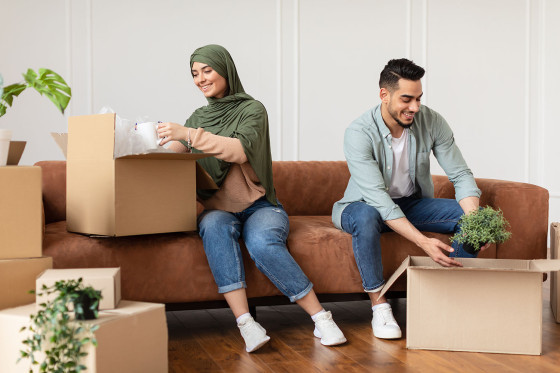 A couple site on a sofa opening boxes 