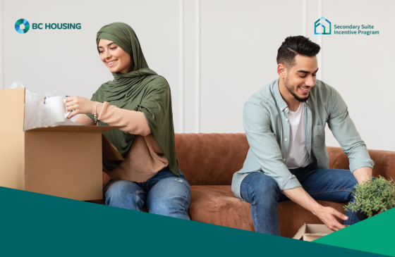 A smiling couple unpacking boxes and decorating their home, promoting the BC Housing Secondary Suite Incentive Program with an application deadline of March 30, 2025.