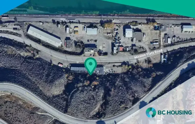 Aerial map showing a site marked with a location pin along Mission Flats Road, with nearby industrial buildings, rail line, curving roads, surrounding vegetation