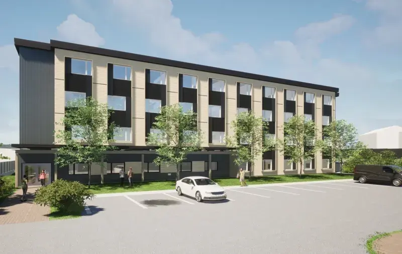 Artist rendering of a three-storey supportive housing building with modern facade, parking area, trees, and people outside.