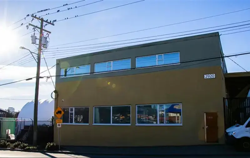Brown two-storey building with a door on the right. Street view, sunny day.